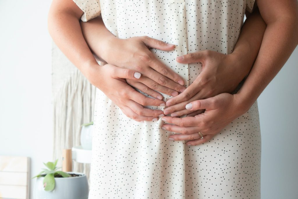 mains enlaçant le ventre d'une maman