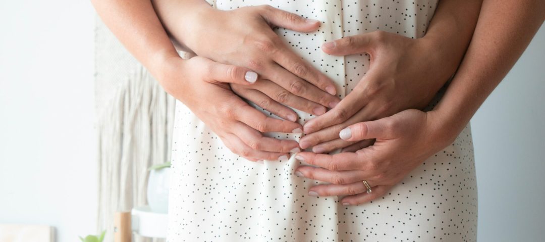 mains enlaçant le ventre d'une maman
